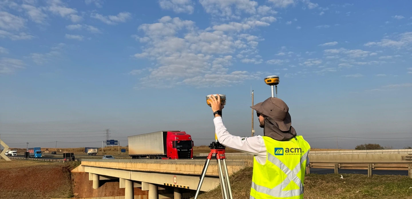 Fotografia de um profissional topografo em uma rodovia